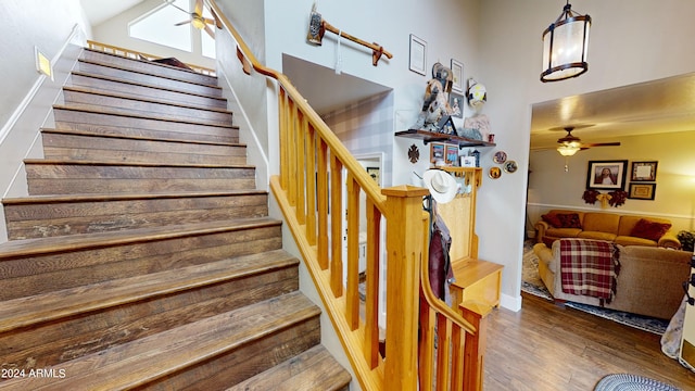 stairs featuring dark hardwood / wood-style flooring, ceiling fan, and a high ceiling