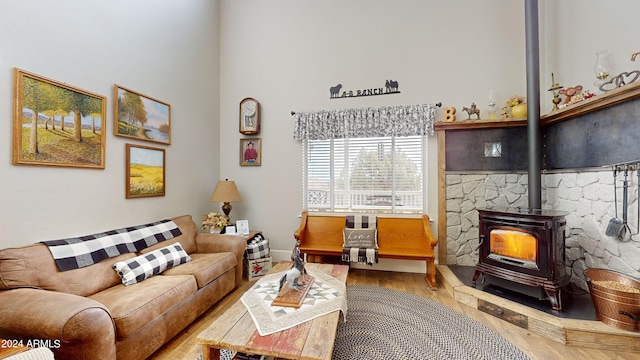 living room with a towering ceiling, light hardwood / wood-style floors, and a wood stove