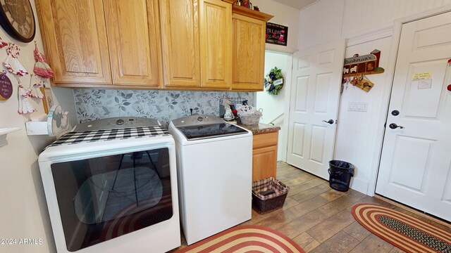 washroom with washing machine and dryer, cabinets, and dark wood-type flooring