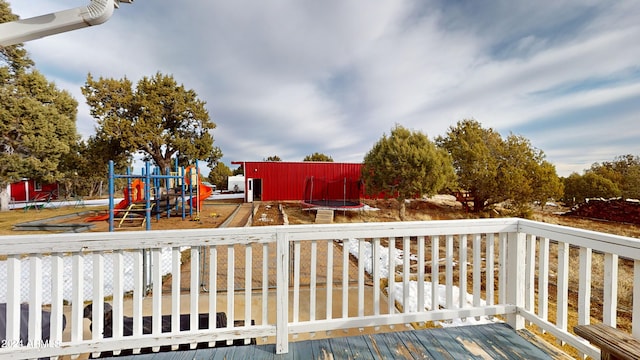 wooden deck featuring a playground and a trampoline