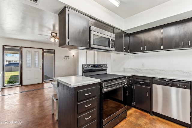 kitchen featuring light stone counters, finished concrete flooring, tasteful backsplash, appliances with stainless steel finishes, and a ceiling fan