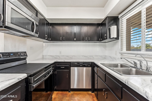 kitchen with backsplash, appliances with stainless steel finishes, a sink, concrete flooring, and dark cabinetry