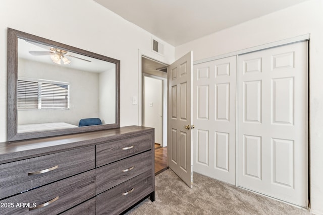 bedroom featuring a ceiling fan, a closet, visible vents, and light carpet