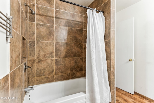 bathroom featuring wood finished floors and shower / bathtub combination with curtain