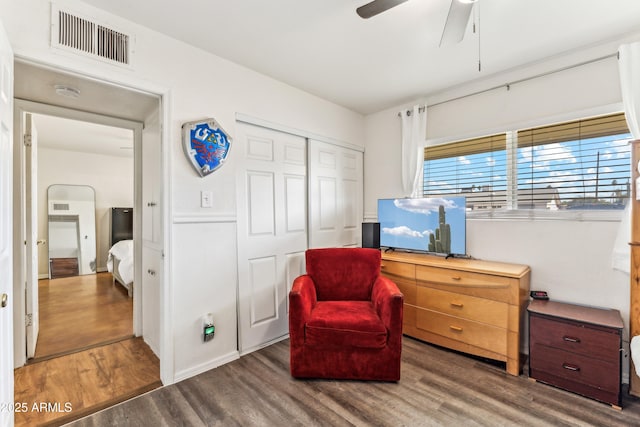 living area featuring a ceiling fan, visible vents, and wood finished floors