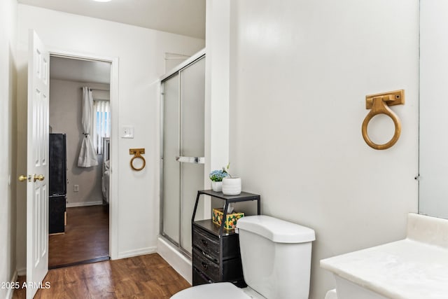 full bathroom featuring toilet, a stall shower, baseboards, and wood finished floors