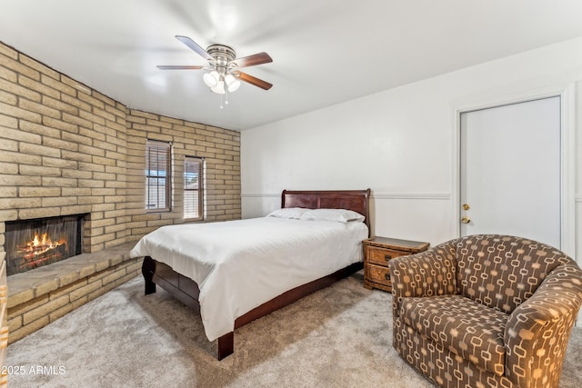 bedroom with carpet floors, a brick fireplace, and a ceiling fan