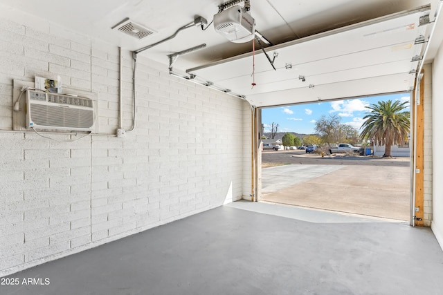 garage with a wall unit AC, visible vents, and a garage door opener