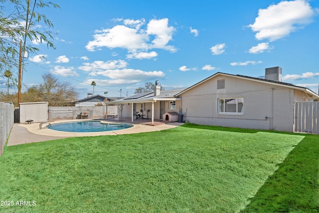 back of property featuring a fenced in pool, a lawn, roof mounted solar panels, a patio area, and a fenced backyard