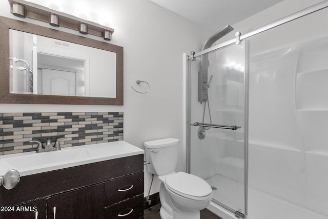 bathroom featuring backsplash, vanity, toilet, and a shower with shower door