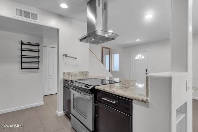 kitchen featuring light stone countertops, island range hood, and range with electric stovetop