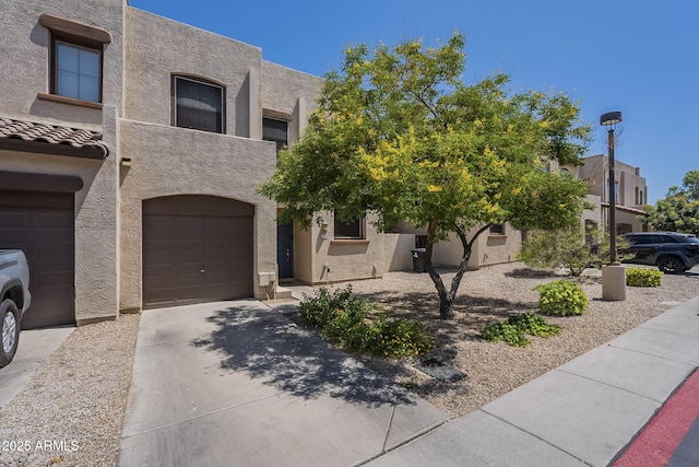 1886 E Don Carlos Ave Unit 136, Tempe, AZ 85281 - view of front facade with stucco siding, driveway, and a garage