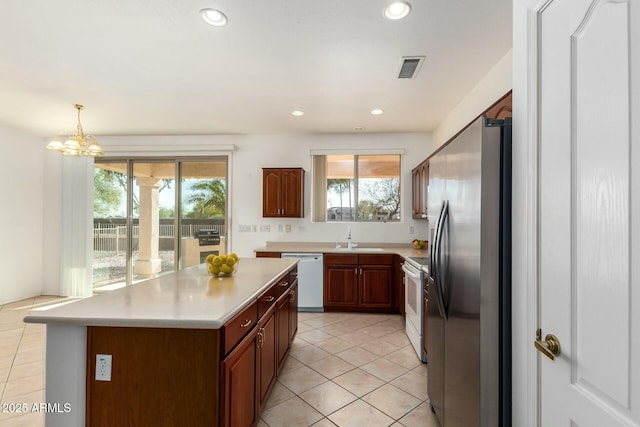 kitchen with sink, hanging light fixtures, light tile patterned floors, a kitchen island, and white appliances