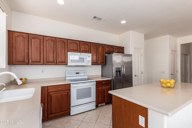 kitchen with white appliances, sink, and light tile patterned floors