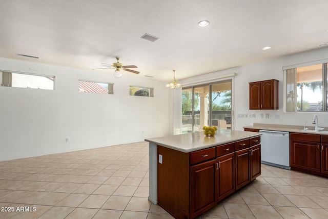 kitchen with sink, hanging light fixtures, white dishwasher, a kitchen island, and a wealth of natural light