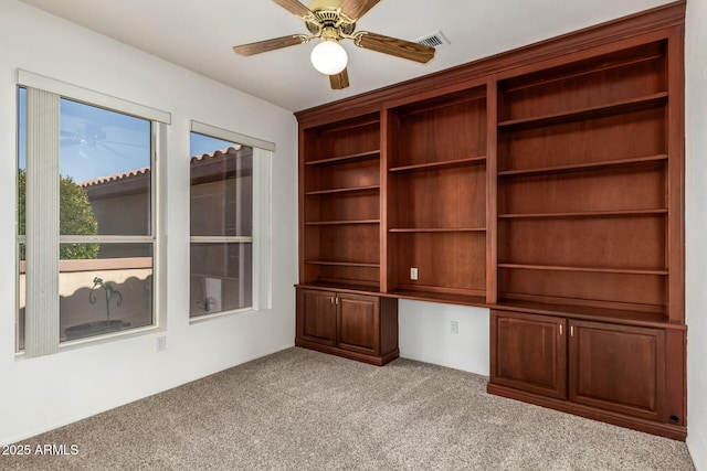 interior space with light carpet, built in desk, and ceiling fan