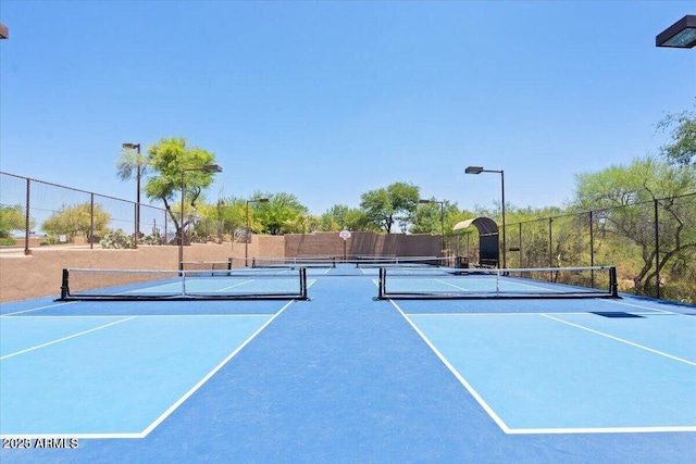 view of tennis court with community basketball court and fence