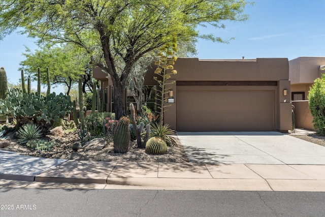 pueblo-style home with stucco siding, concrete driveway, and an attached garage