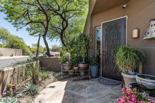 property entrance with fence, a patio area, and stucco siding