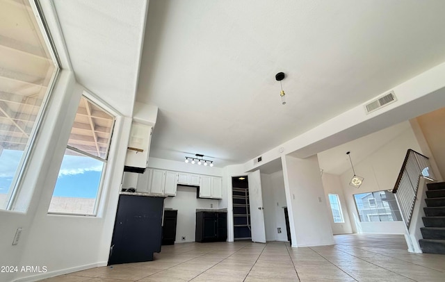 unfurnished living room with light tile patterned floors, vaulted ceiling, and track lighting