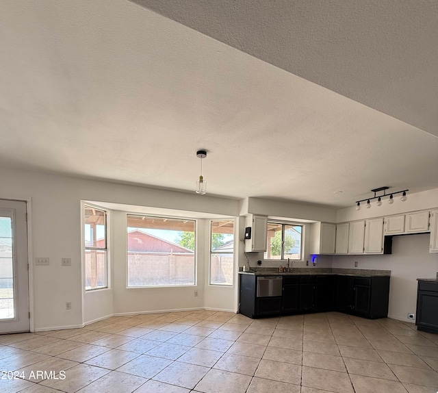 kitchen with white cabinetry, a textured ceiling, hanging light fixtures, light tile patterned floors, and stainless steel dishwasher