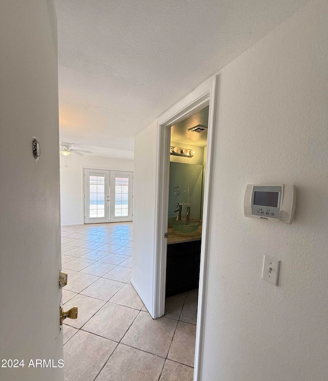 hall with sink, light tile patterned floors, french doors, and a textured ceiling