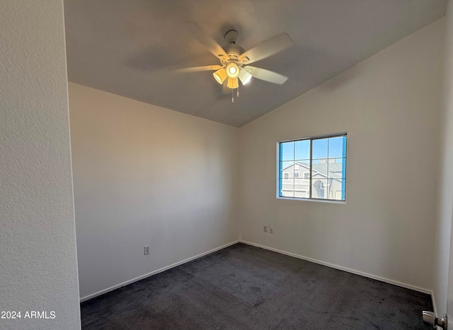 empty room with dark colored carpet, vaulted ceiling, and ceiling fan