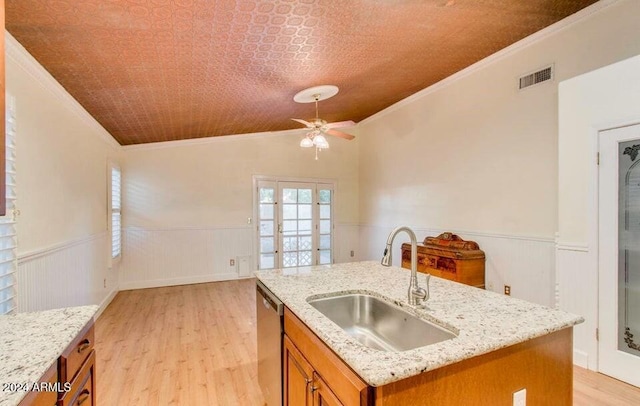 kitchen featuring sink, light stone counters, crown molding, a center island with sink, and light wood-type flooring