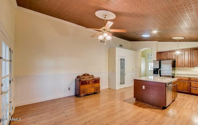 kitchen featuring appliances with stainless steel finishes, ornamental molding, vaulted ceiling, light hardwood / wood-style flooring, and an island with sink