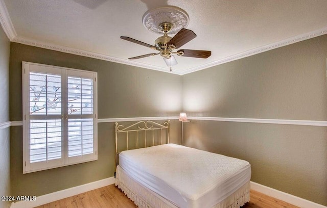 bedroom featuring ceiling fan, light hardwood / wood-style flooring, and crown molding