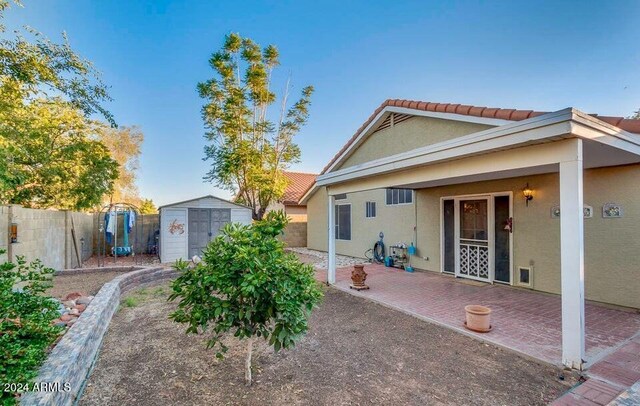 back of property featuring a patio area and a storage shed