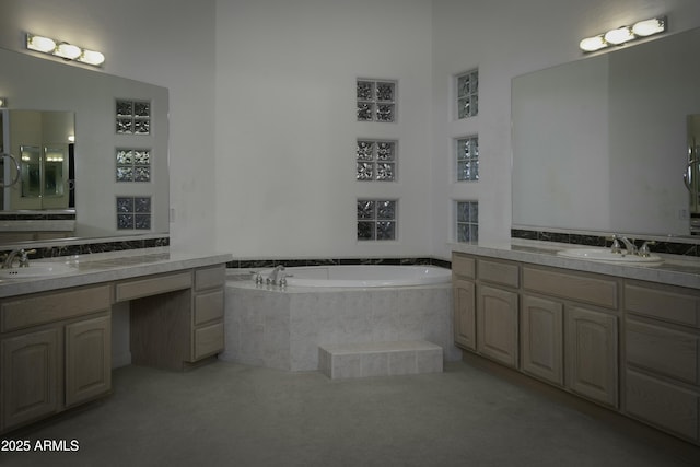 bathroom featuring a relaxing tiled tub and vanity