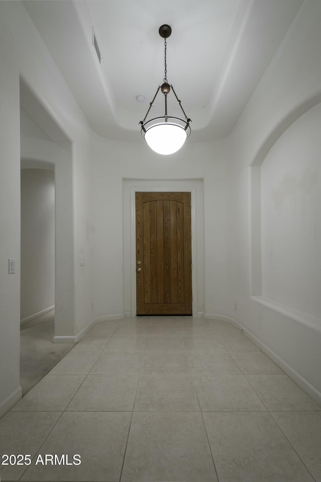 interior space featuring light tile patterned flooring and a tray ceiling