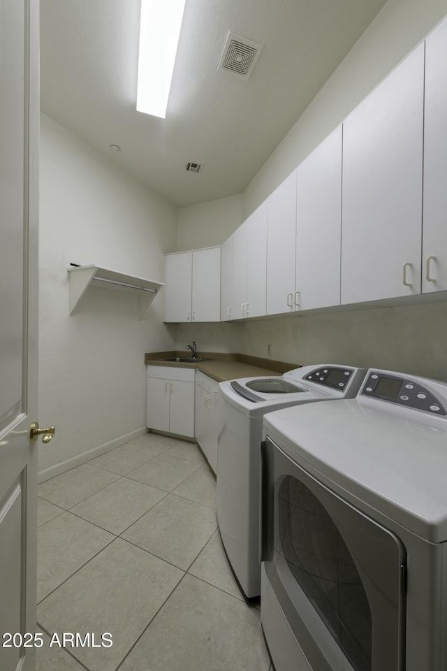 washroom with cabinets, washing machine and dryer, sink, and light tile patterned floors