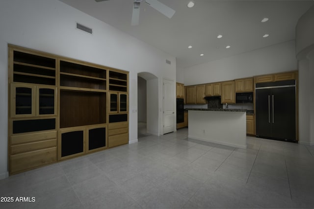 kitchen with ceiling fan, paneled built in refrigerator, a center island, a high ceiling, and light tile patterned flooring