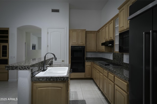 kitchen featuring sink, black appliances, an island with sink, and light tile patterned flooring