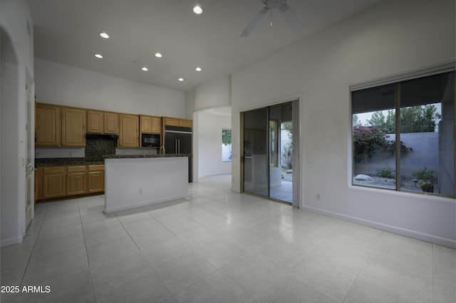 kitchen with decorative backsplash, a high ceiling, a center island, ceiling fan, and black appliances