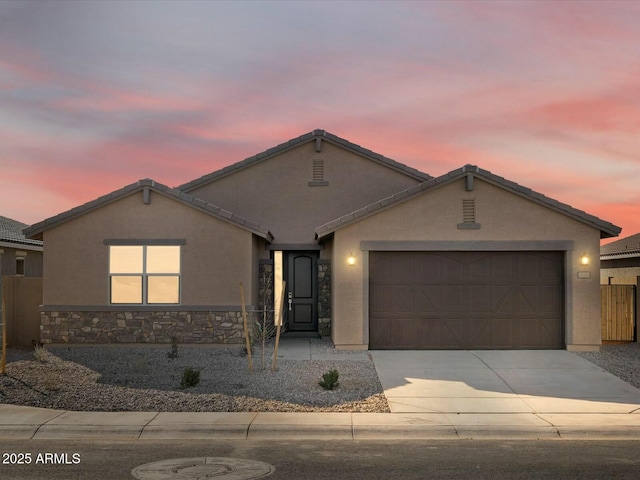 ranch-style house with stucco siding, stone siding, fence, concrete driveway, and a garage