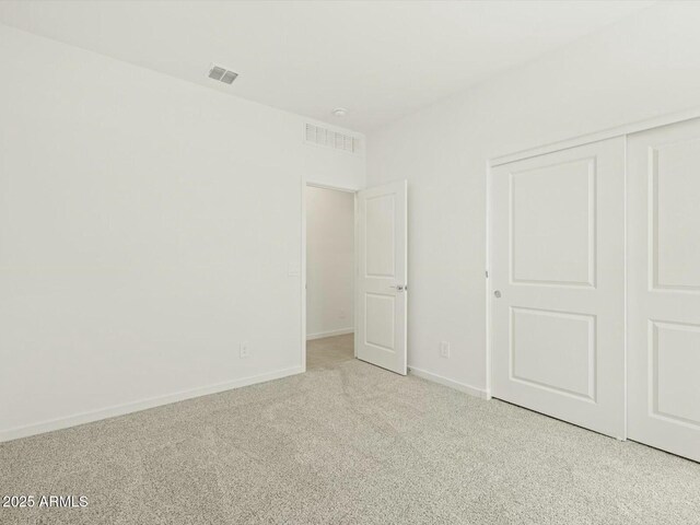 unfurnished bedroom featuring visible vents, carpet floors, baseboards, and a closet