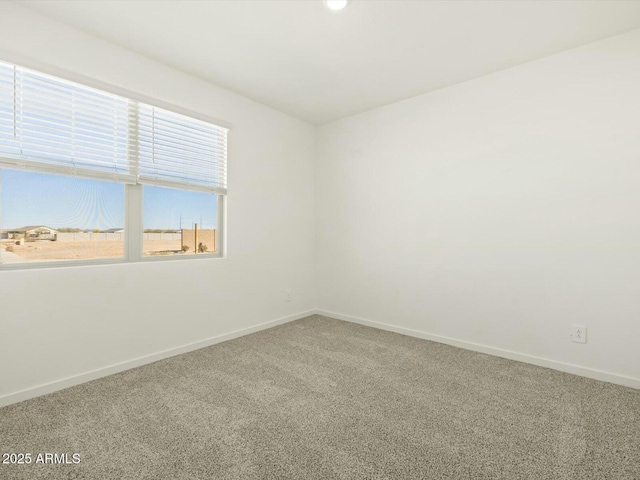 carpeted empty room featuring baseboards