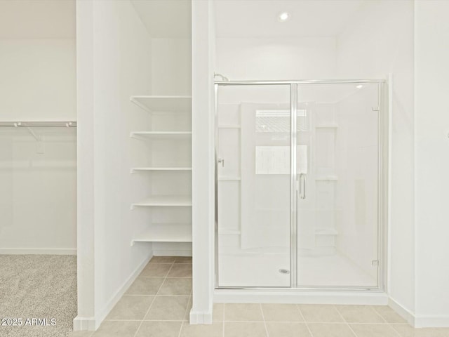 bathroom with baseboards, a stall shower, a spacious closet, and tile patterned flooring