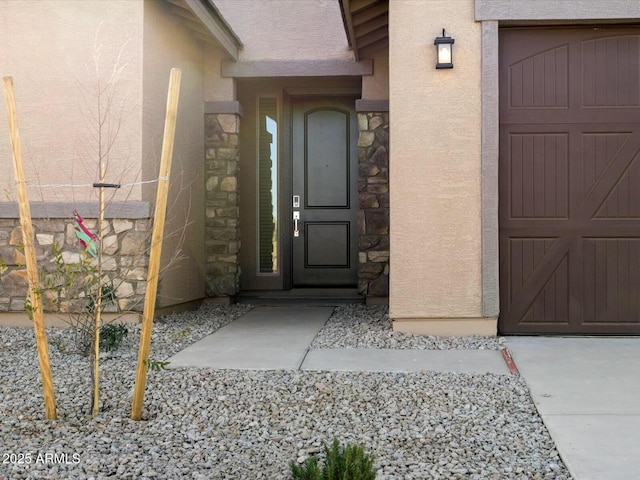 property entrance featuring stucco siding, stone siding, and a garage