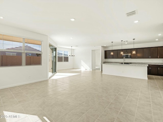 unfurnished living room featuring light tile patterned floors, baseboards, visible vents, recessed lighting, and a sink