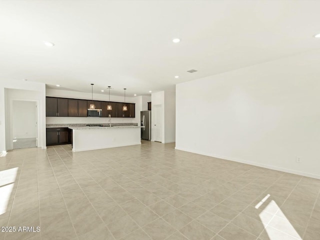 unfurnished living room featuring visible vents, recessed lighting, baseboards, and a sink