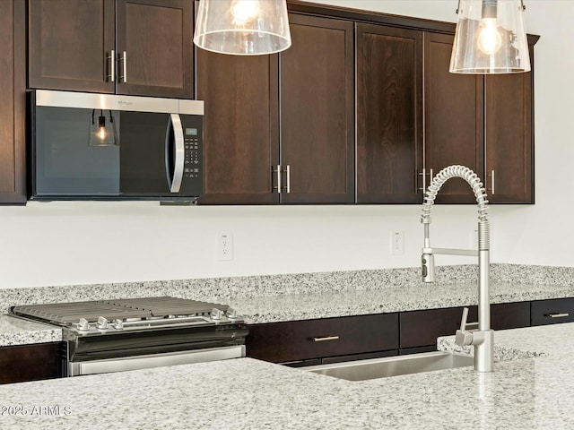 kitchen featuring hanging light fixtures, dark brown cabinets, and appliances with stainless steel finishes