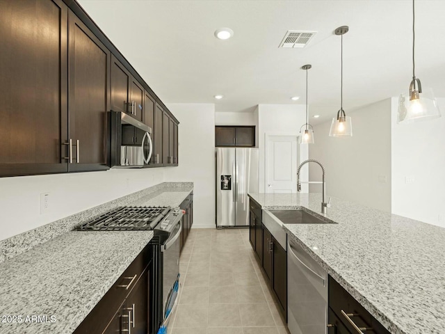 kitchen with light stone countertops, visible vents, appliances with stainless steel finishes, and a sink