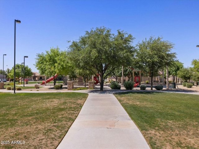 view of property's community featuring playground community and a yard