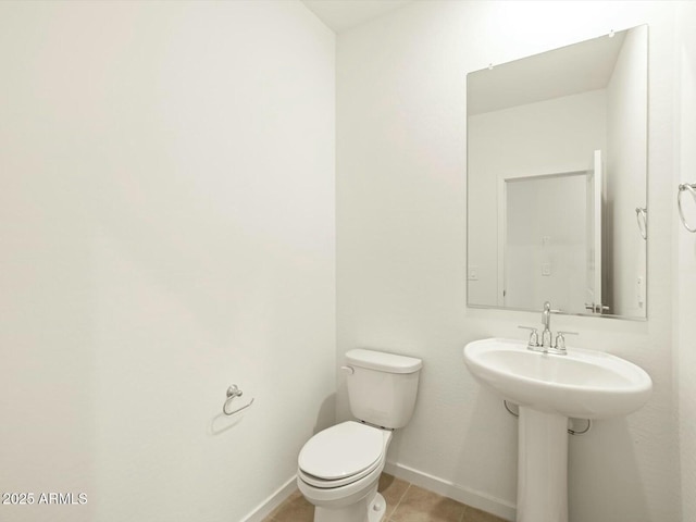 half bathroom featuring tile patterned floors, toilet, and baseboards