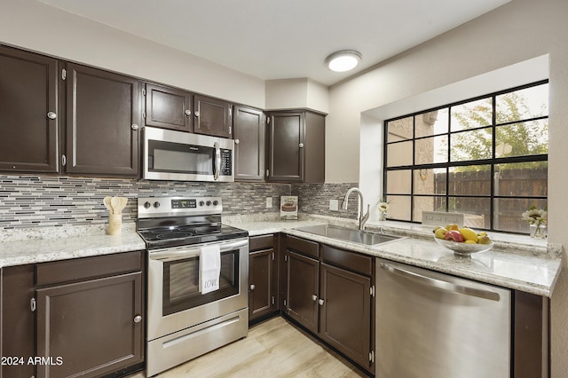 4901 E Kelton Ln Unit 1006, Scottsdale, AZ 85254 - kitchen featuring stainless steel appliances, tasteful backsplash, dark brown cabinetry, light wood finished floors, and light stone counters