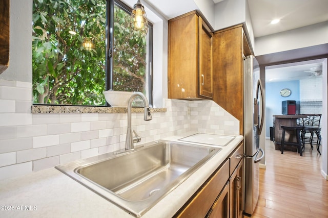 kitchen featuring light hardwood / wood-style flooring, stainless steel fridge, backsplash, and sink